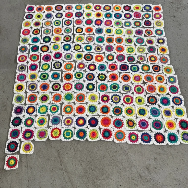 Viele bunte gehäkelte Granny Squares, zu einer Decke ausgelegt