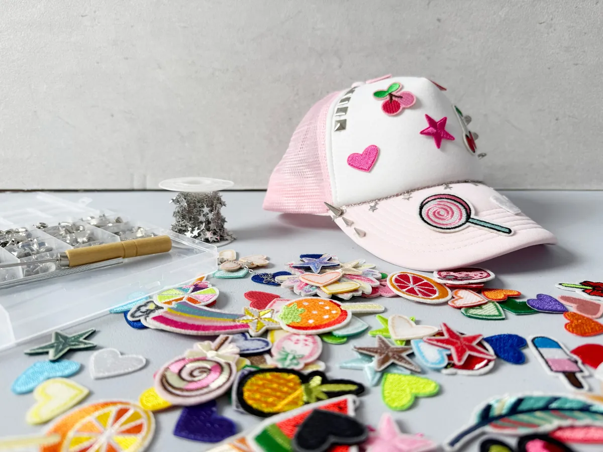 Trucker-Cap mit Patches und Nieten, davor bunte Aufnäher und Nieten-Box