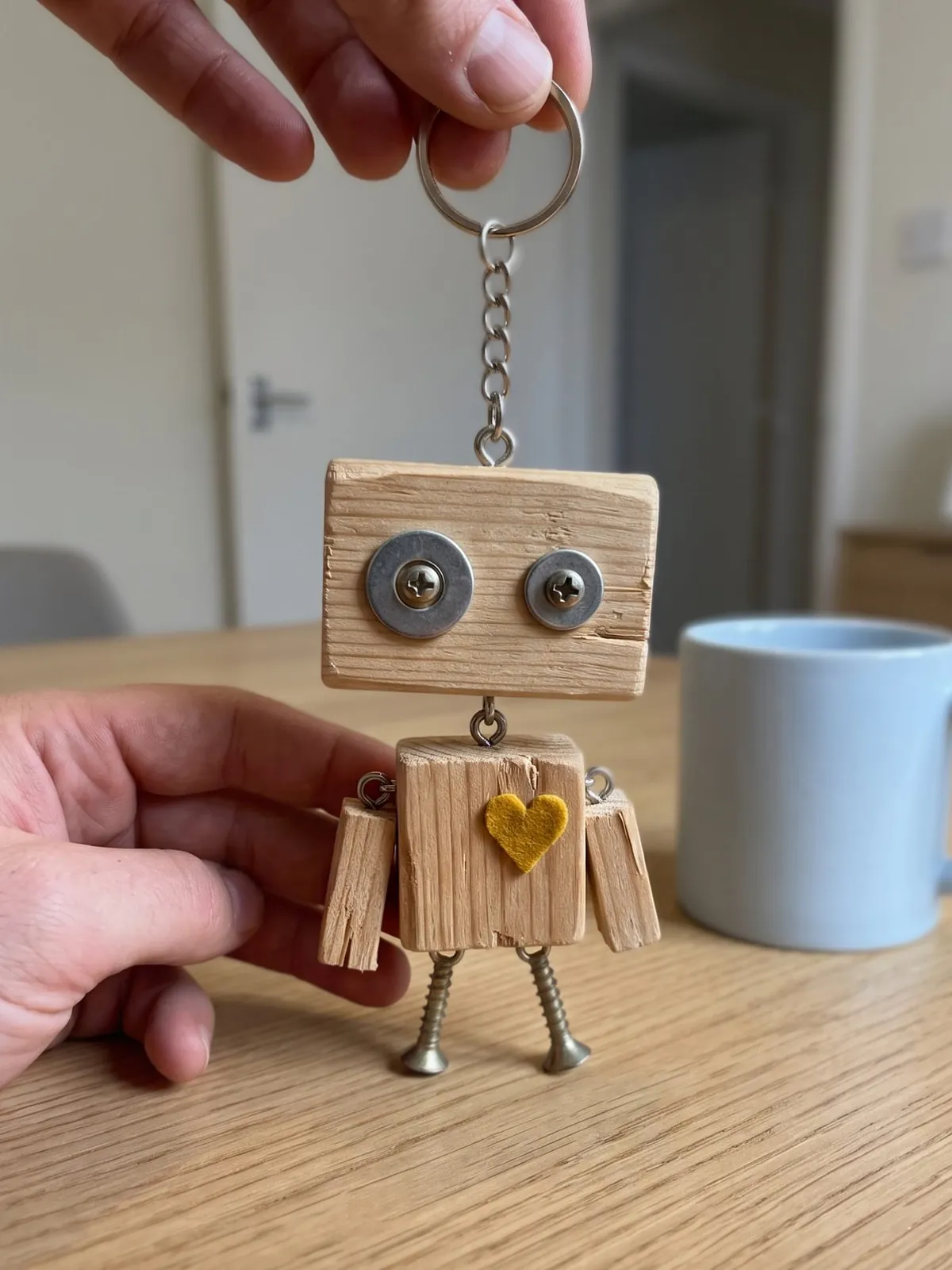 Holzroboter mit Schrauben-Augen, Filzherz und Schraubenfüßen auf einem Küchentisch