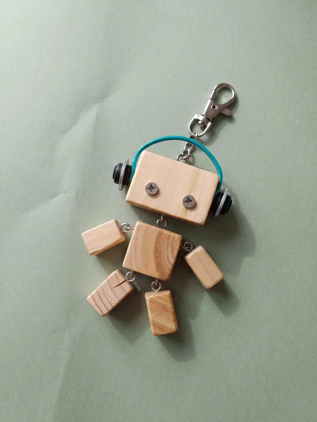Holzroboter mit Kopfhörern aus Draht auf salbeigrünem Papier
